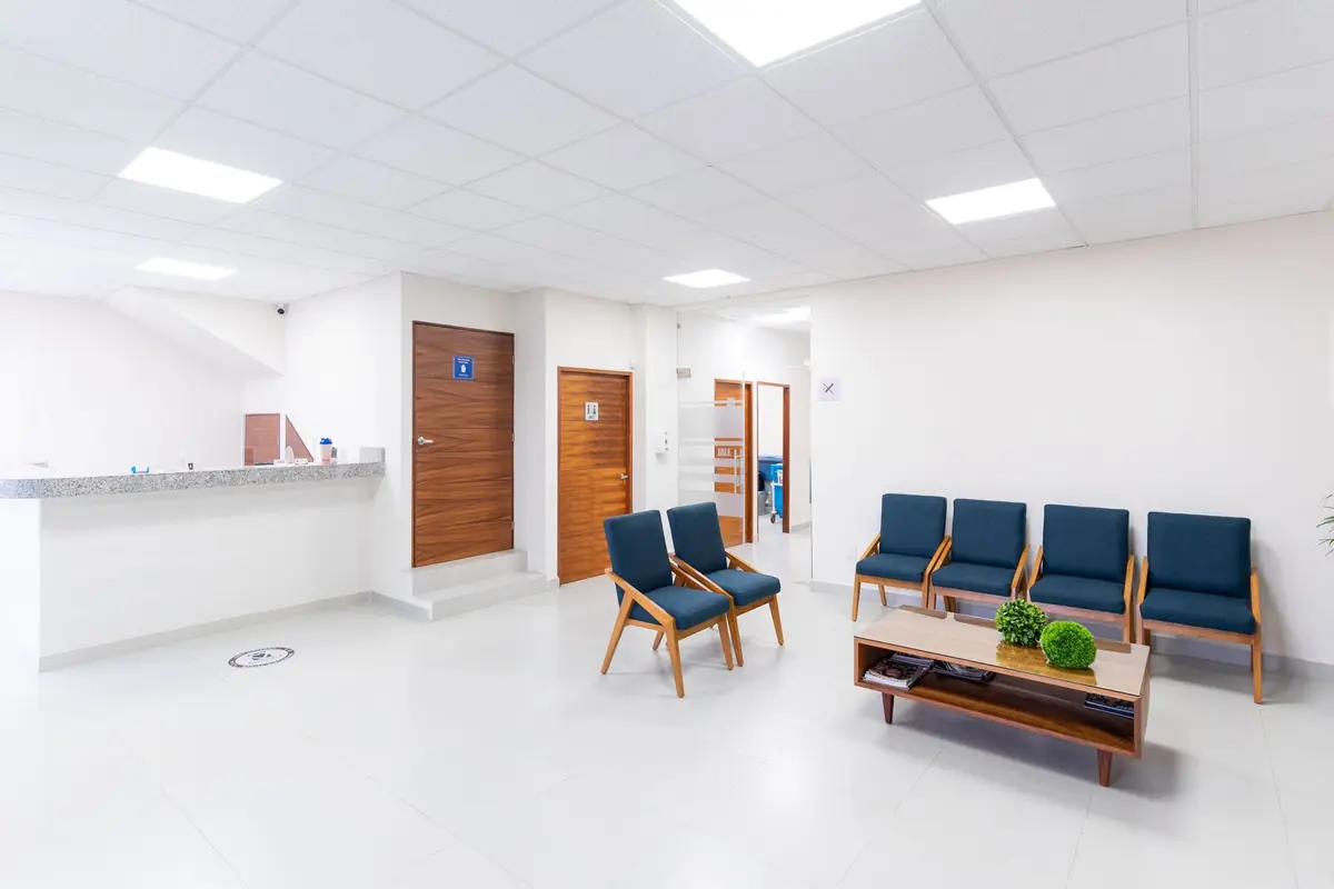 A bright, quiet clinic waiting area with wooden seating and a reception desk