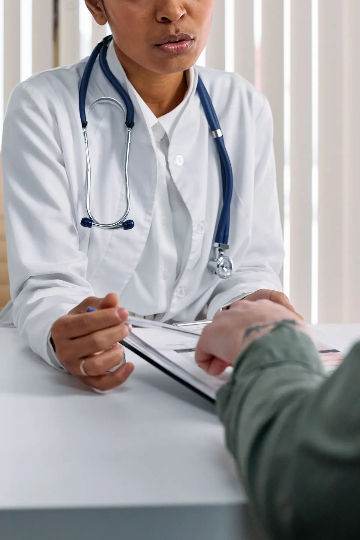 A clinician talking with a patient across a consulting-room desk