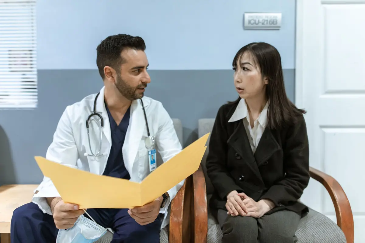 A clinician reviewing notes at a desk with a patient seated alongside