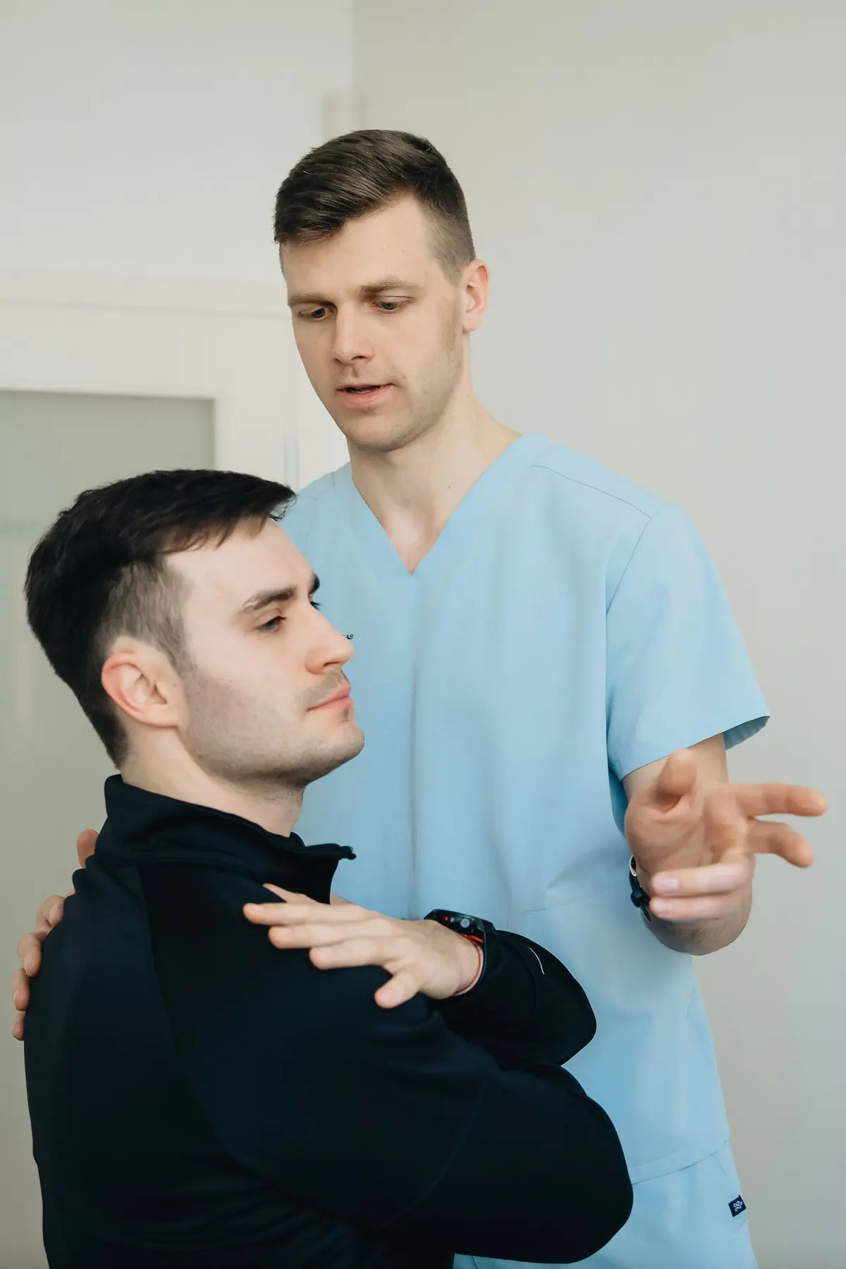 A physiotherapist guiding a patient through a movement assessment in a treatment room